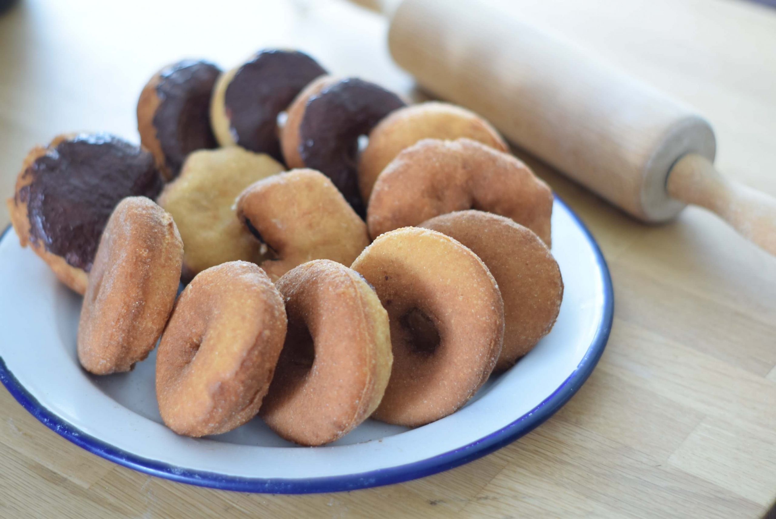 Freshly baked sourdough doughnuts on an enamel plate with a blue rim