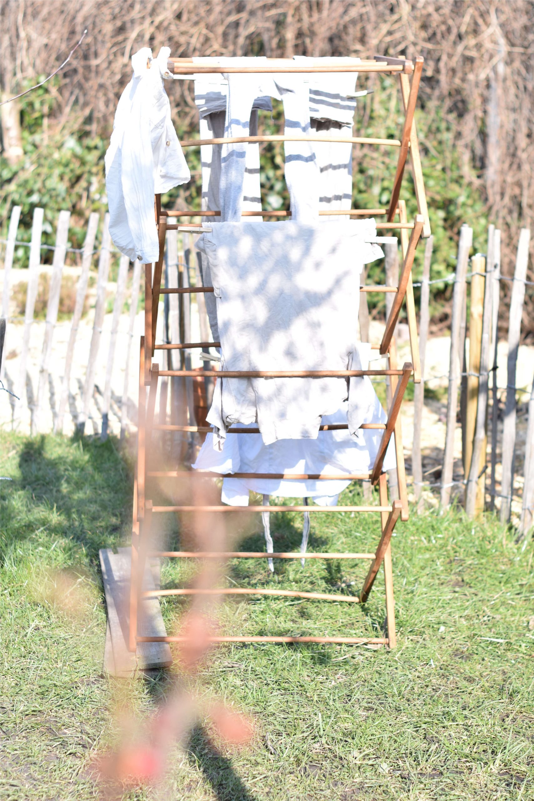 Antique wooden clothing rack with white linen clothes