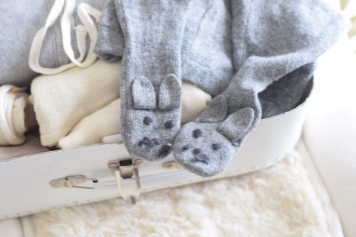 White suitcase with a baby legging on a woolen mat