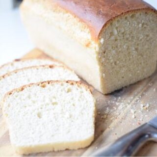 A close-up of a slice of light and fluffy sandwich bread on a wooden cutting board.