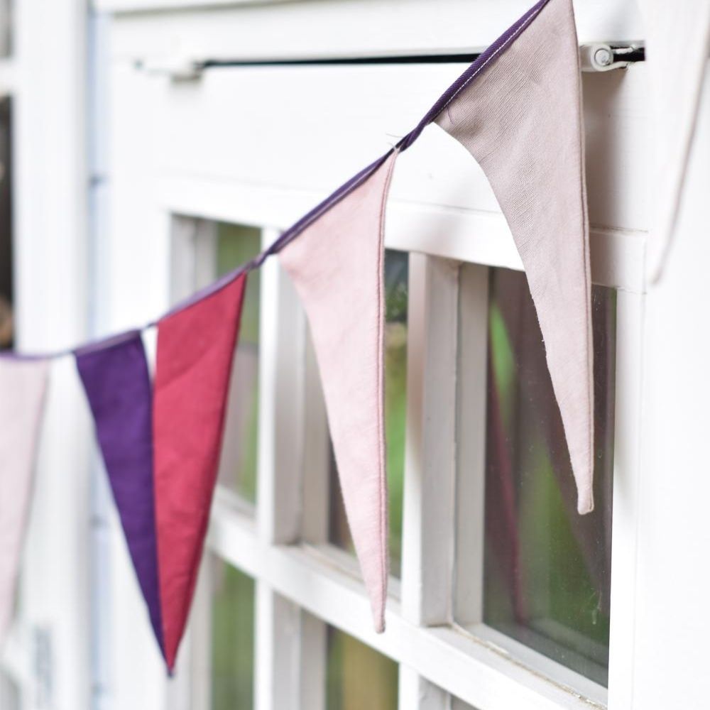 Close-up of handmade linen bunting flags gracefully hanging from a window, adding a charming touch to the space.