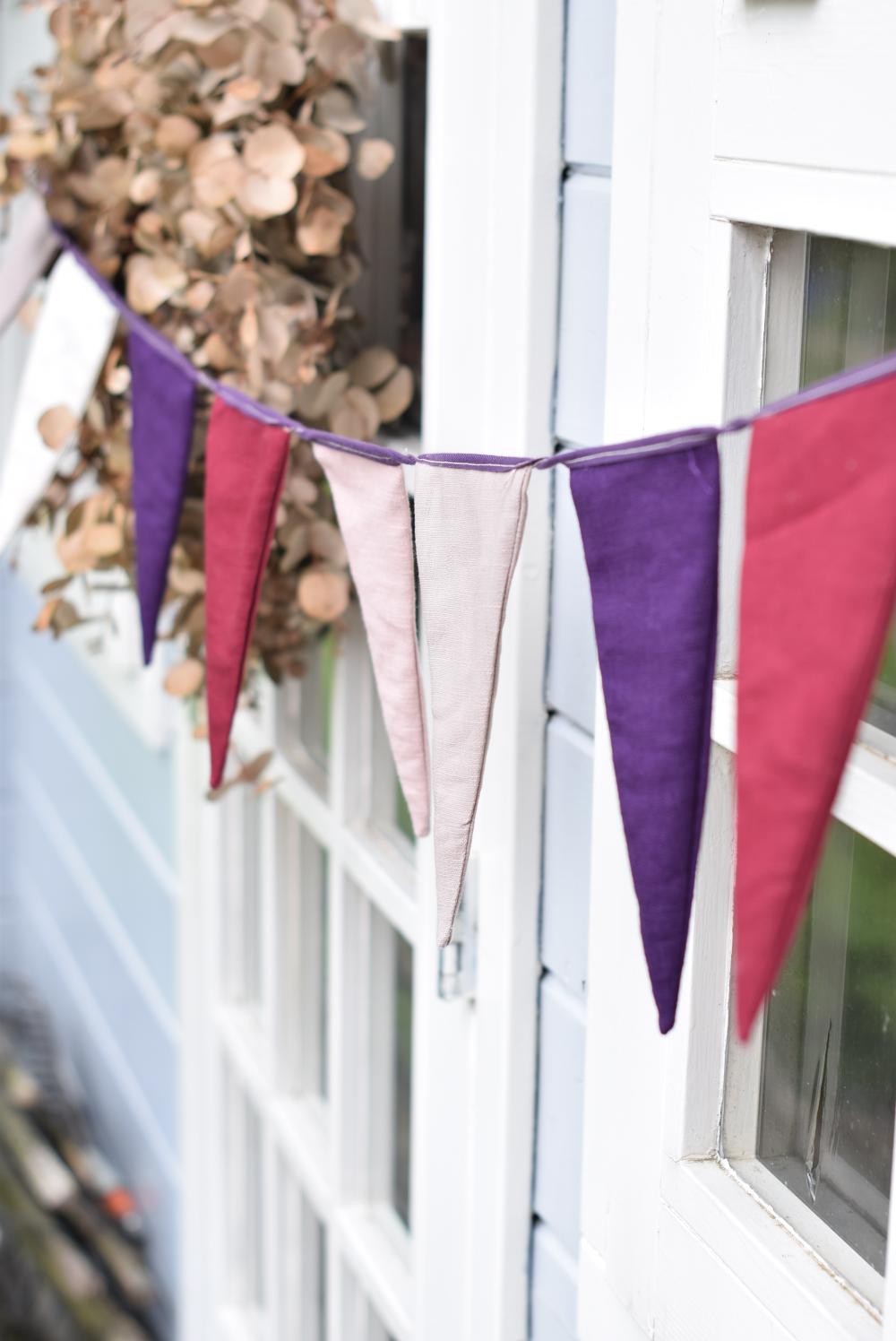 Linen bunting in the wind. With purple, pink and red colored triangle shapes