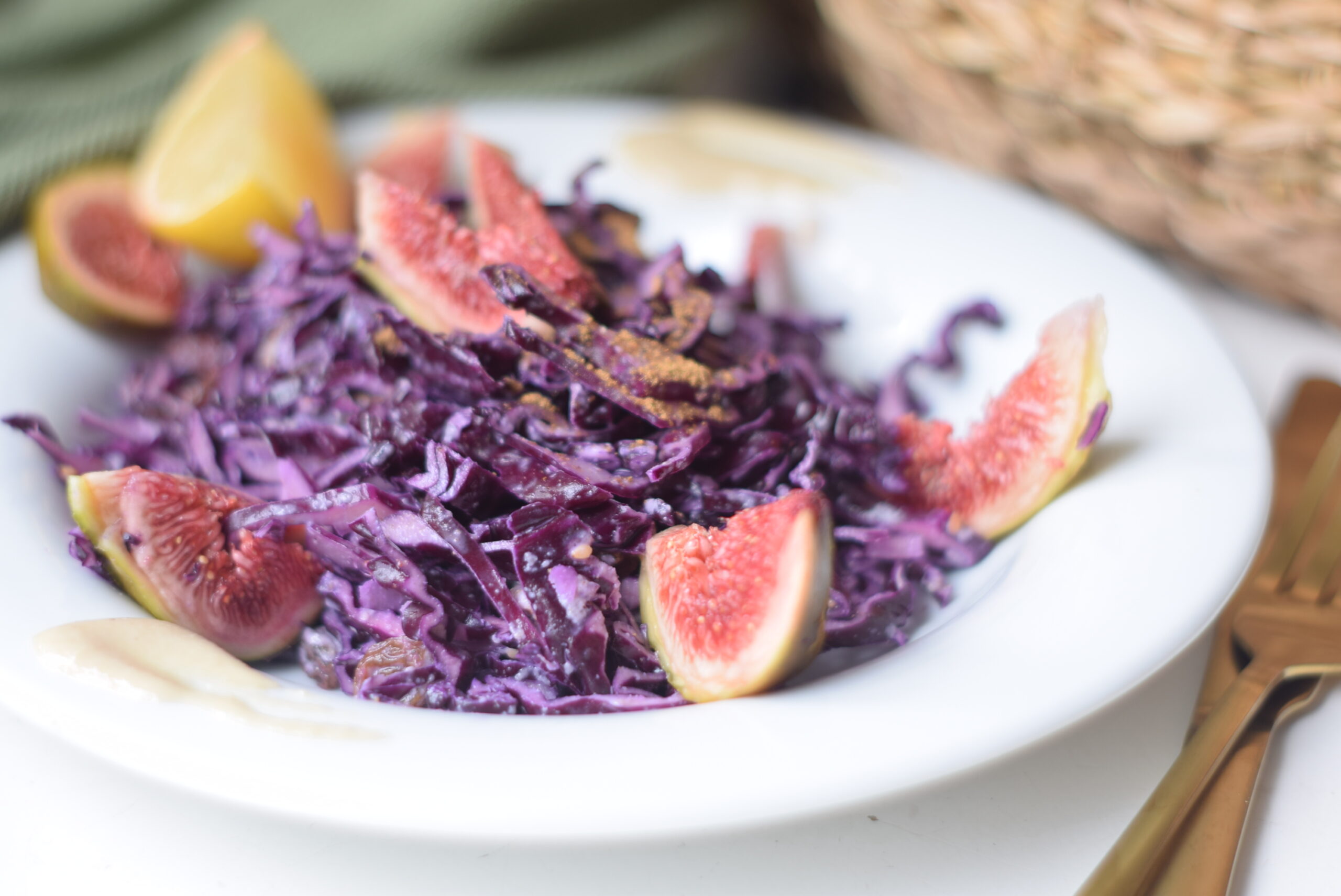 A vibrant red cabbage salad mixed with raisins, sesame seeds, and a creamy tahini dressing