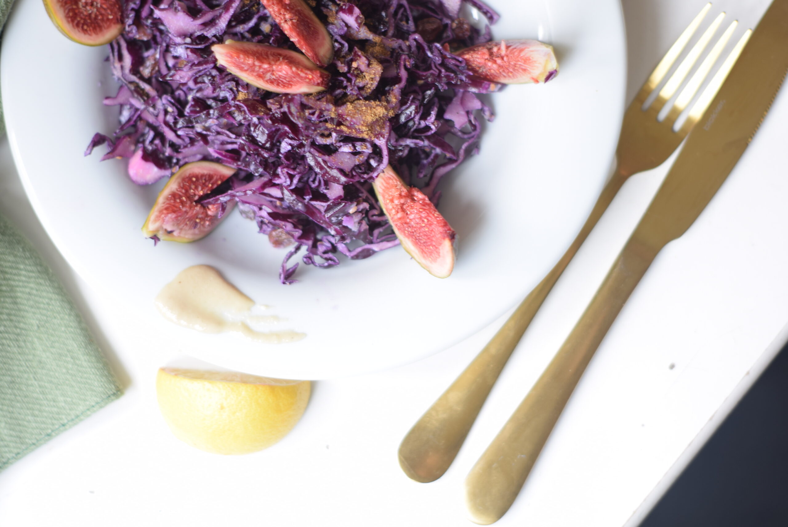 Close-up of warm red cabbage salad with raisins, sesame seeds, and a drizzle of garam masala tahini dressing.