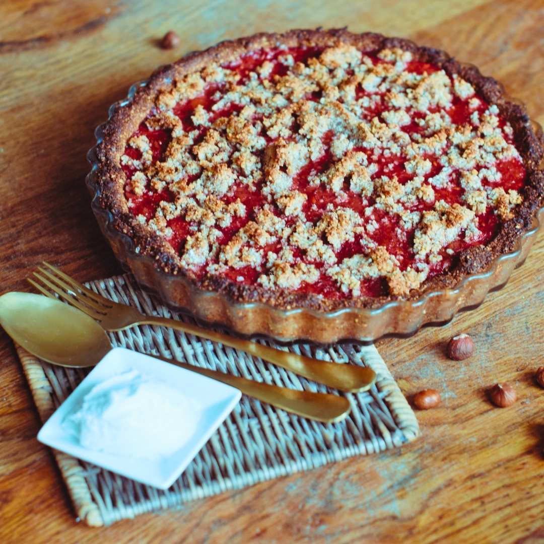 Strawberry gooseberry pie recipe with a golden fork, spoon, and a generous dollop of coconut cream for topping.