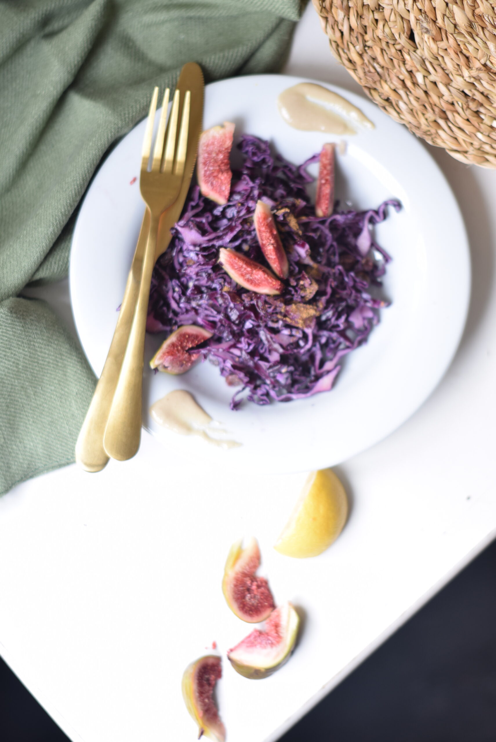 Warm red cabbage salad with a garam masala tahini dressing, sesame seeds, and figs & lemon slices for garnish.