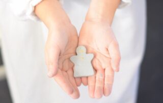 Two hands gently holding a handmade clay gingerbread man ornament, a thoughtful and creative Christmas gift.