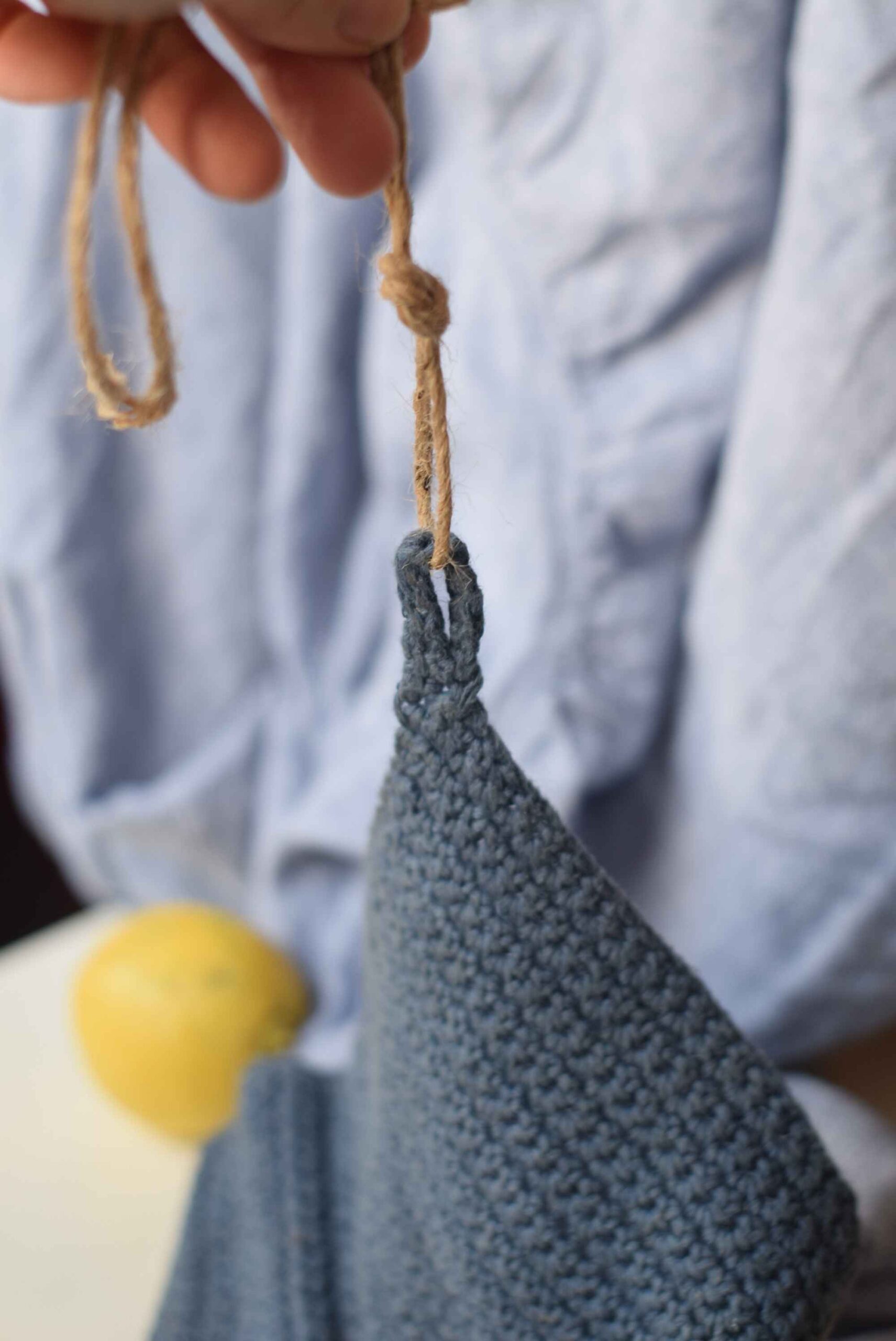 A sustainable blue linen dishcloth displayed on a white surface with lemons and a loop.