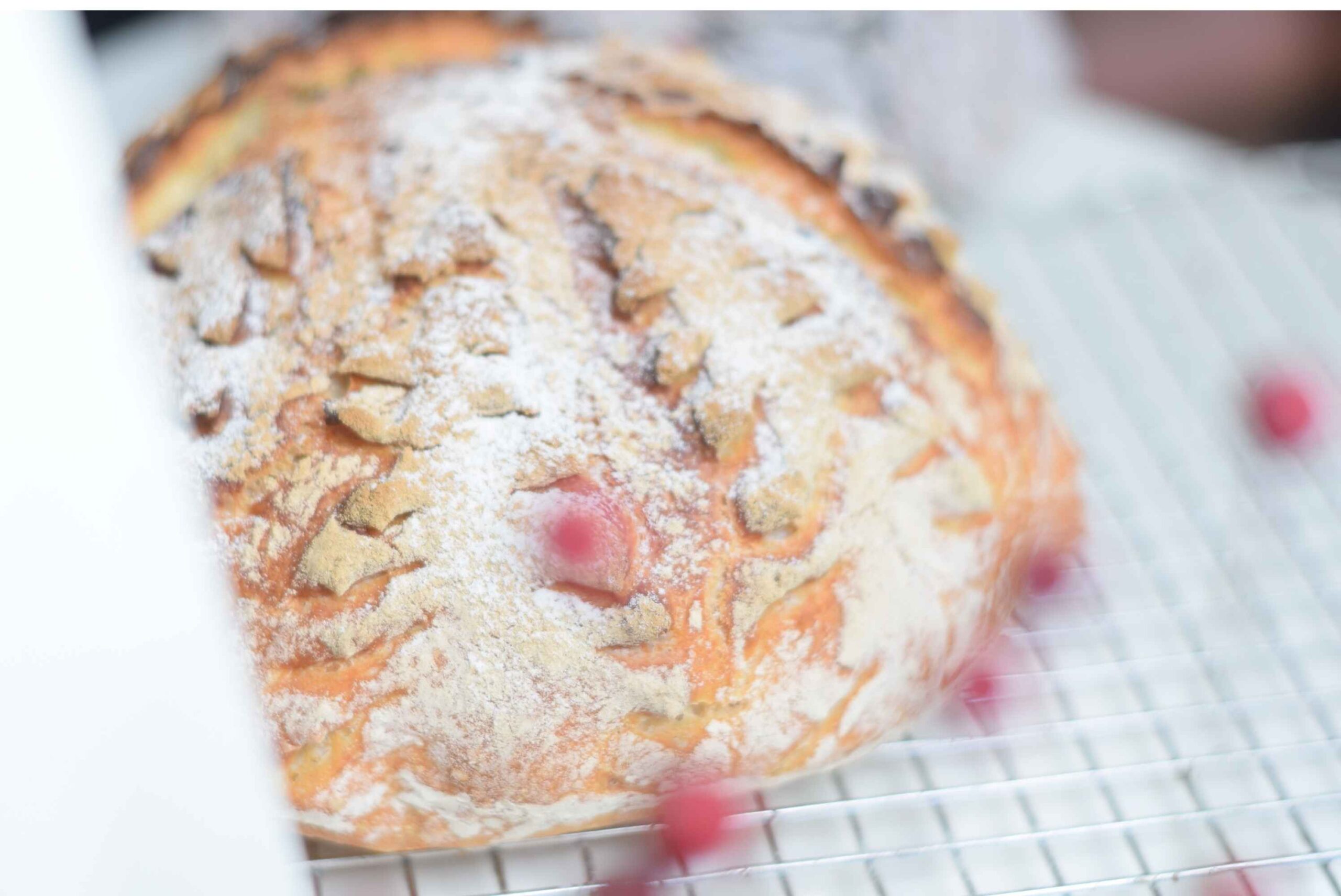 Scored bread with a spruce scoring pattern. Red berries in the front.