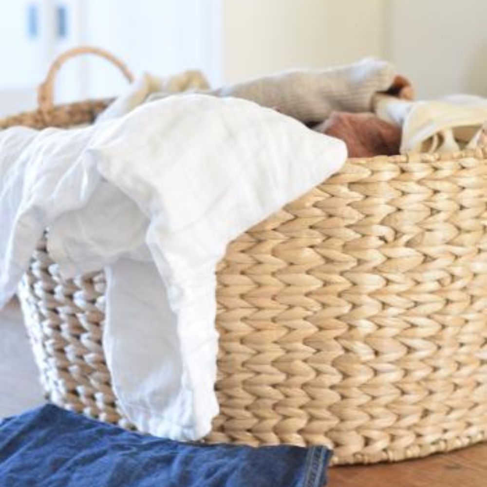 A cozy basket overflowing with freshly laundered clothes resting on a warm wooden table, perfect for laundry day tips.