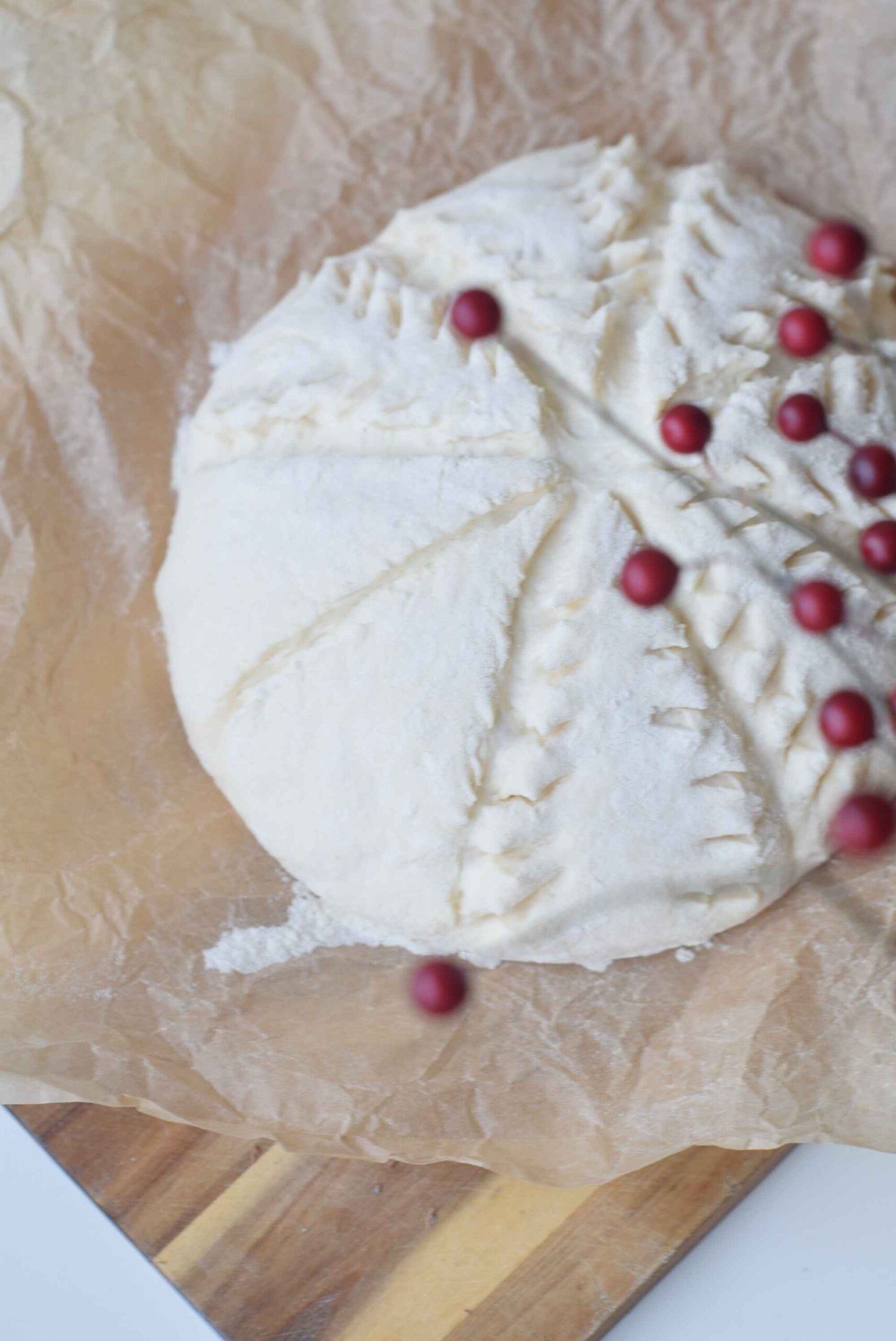 Close-up of a round loaf of spelt bread with decorative spruce pattern scoring, lightly dusted with flour.